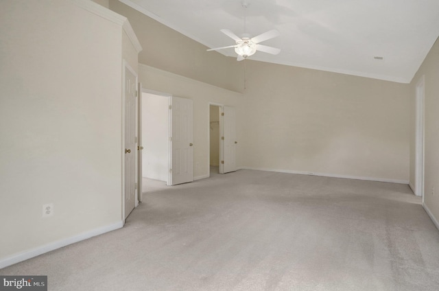 empty room with baseboards, light carpet, crown molding, lofted ceiling, and ceiling fan