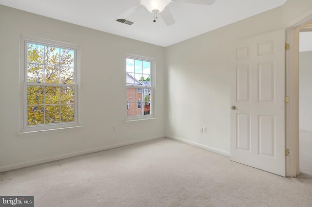carpeted spare room featuring visible vents, baseboards, and ceiling fan