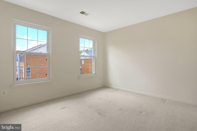 empty room featuring carpet, visible vents, and baseboards