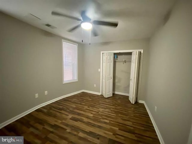 unfurnished bedroom featuring a closet, a ceiling fan, baseboards, visible vents, and dark wood-style flooring