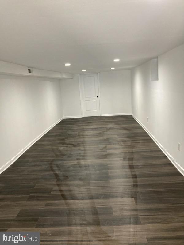 finished below grade area featuring recessed lighting, baseboards, visible vents, and dark wood finished floors