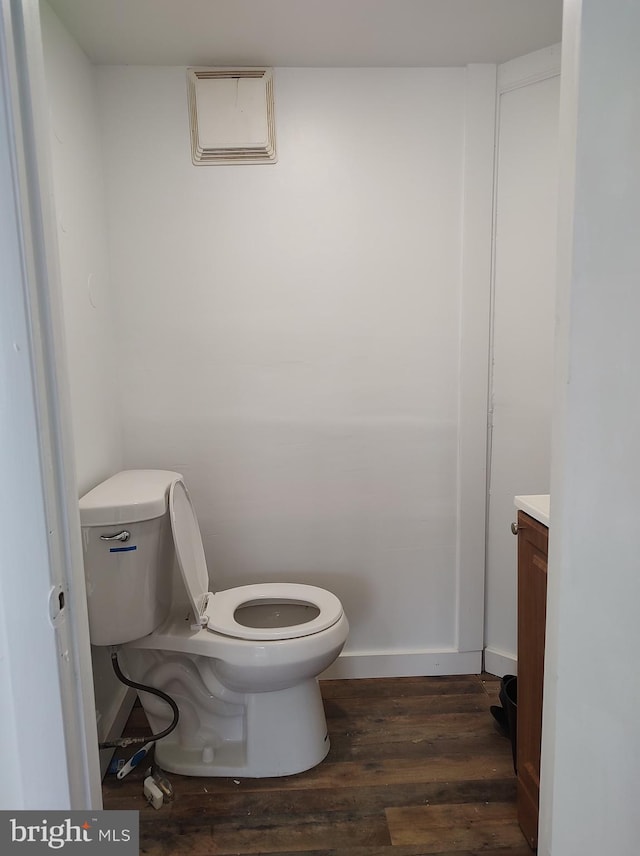 bathroom featuring baseboards, toilet, vanity, and wood finished floors