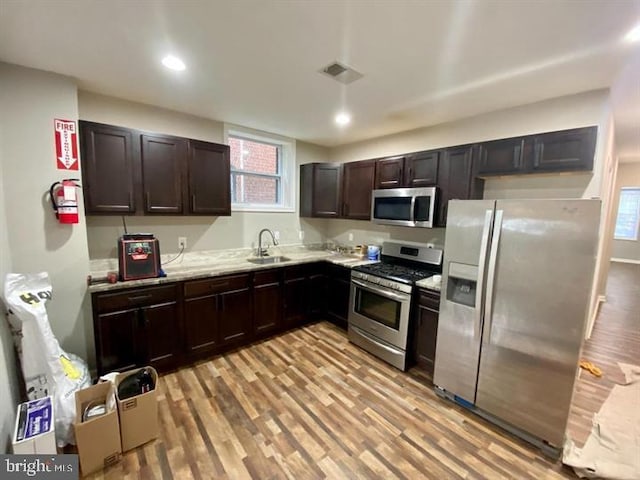 kitchen featuring light wood-style flooring, a sink, stainless steel appliances, and visible vents