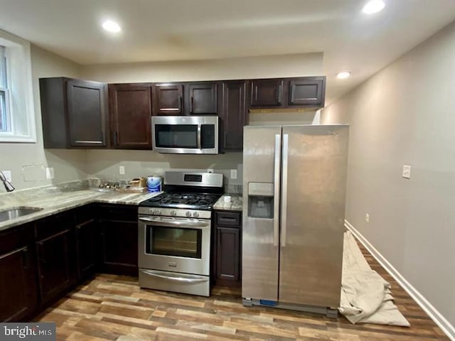 kitchen featuring baseboards, light wood-style flooring, stainless steel appliances, and recessed lighting