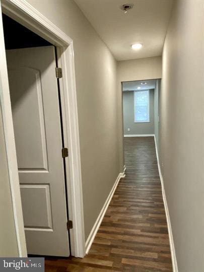 hallway featuring baseboards and dark wood-style flooring
