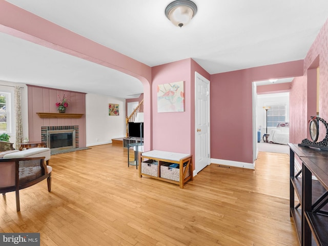 600 Maplewood Rd, Springfield, PA 19064 - living area featuring arched walkways, a fireplace, baseboards, light wood finished floors, and stairs