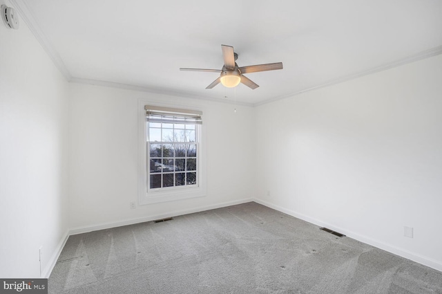 carpeted spare room featuring visible vents, baseboards, crown molding, and ceiling fan