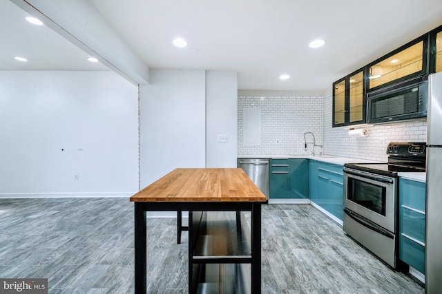 kitchen featuring decorative backsplash, appliances with stainless steel finishes, light wood-type flooring, a sink, and light countertops