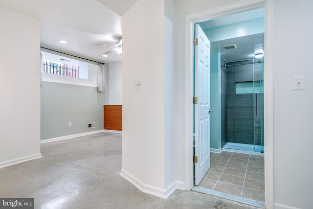 hallway with visible vents, concrete floors, and baseboards
