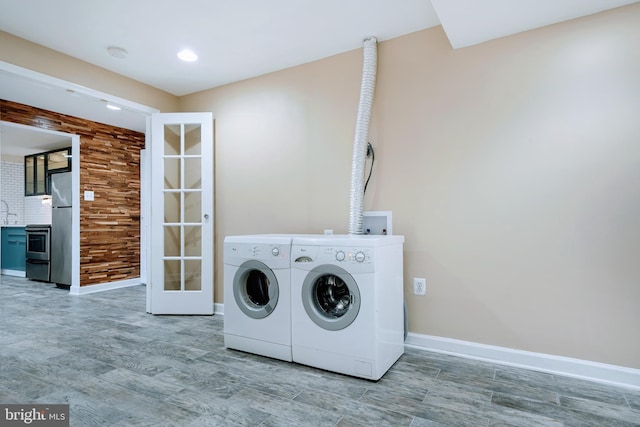 laundry area with baseboards, laundry area, independent washer and dryer, and wood finished floors