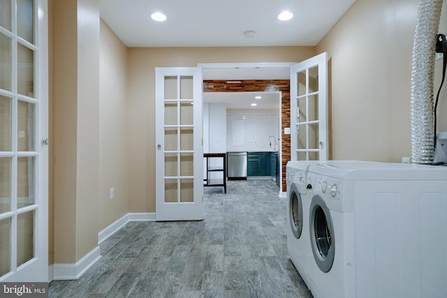washroom featuring washer and dryer, laundry area, light wood finished floors, french doors, and baseboards