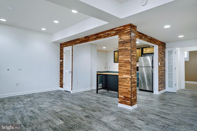 unfurnished living room with a sink, baseboards, recessed lighting, and dark wood finished floors