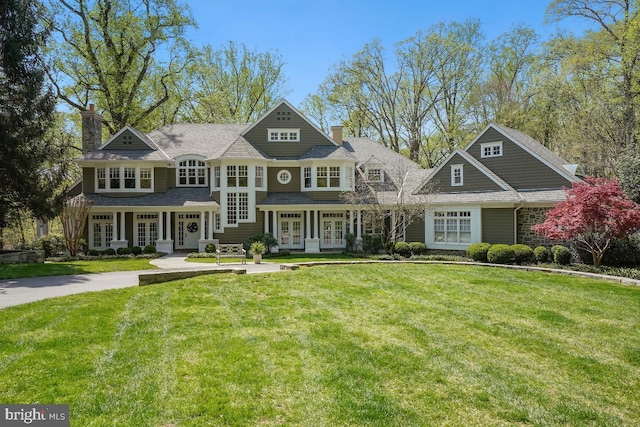 view of front facade featuring french doors, a front yard, and a chimney