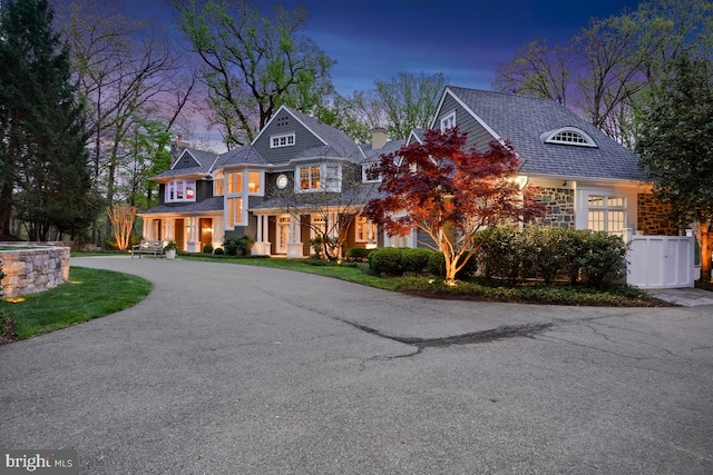 shingle-style home featuring curved driveway and a chimney