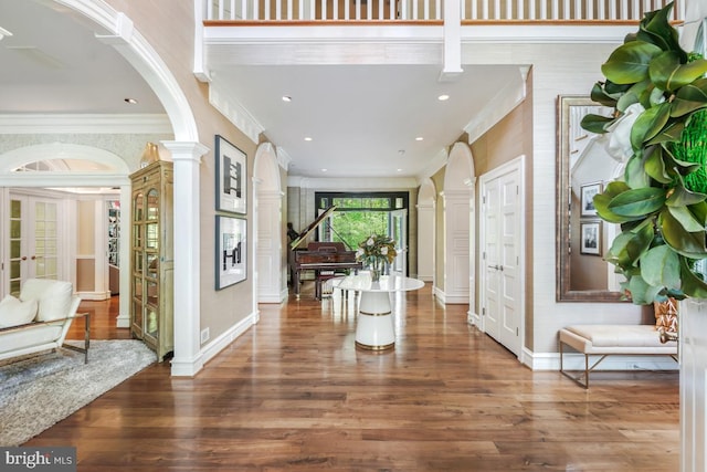 entryway with arched walkways, french doors, decorative columns, wood finished floors, and ornamental molding