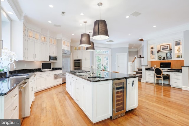 kitchen with a sink, white cabinets, beverage cooler, and crown molding