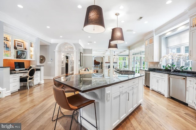 kitchen with crown molding, a breakfast bar, built in desk, white cabinets, and stainless steel appliances