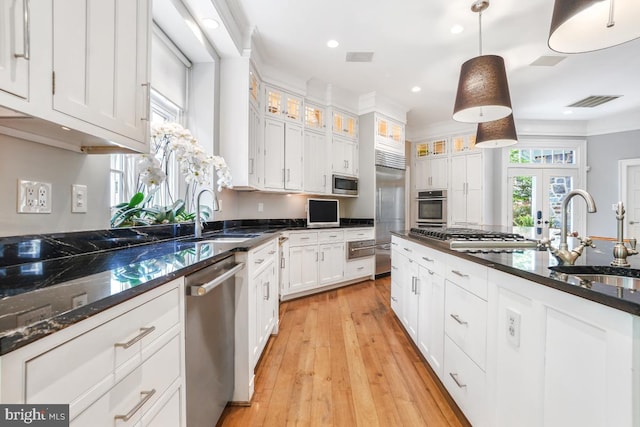 kitchen featuring built in appliances, white cabinetry, a sink, and a warming drawer