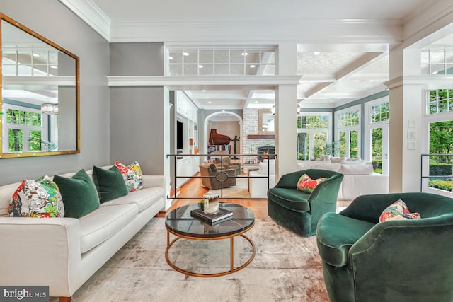 living room with a stone fireplace, wood finished floors, beamed ceiling, ornamental molding, and coffered ceiling