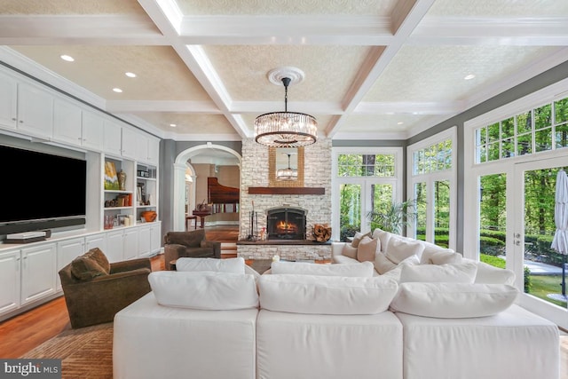 living room with plenty of natural light, light wood finished floors, and a notable chandelier