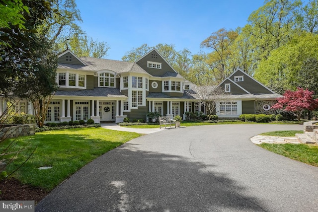 shingle-style home featuring french doors and a front yard