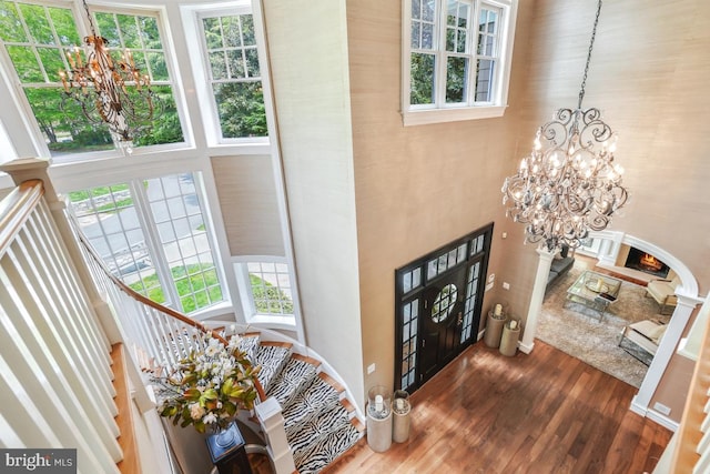foyer entrance featuring an inviting chandelier, wood finished floors, stairway, and a towering ceiling