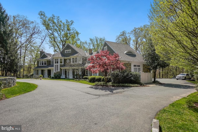shingle-style home with a chimney and aphalt driveway