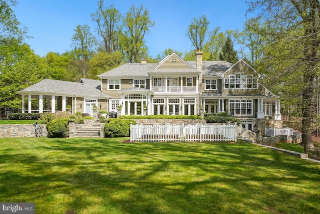 rear view of house featuring a lawn and a balcony