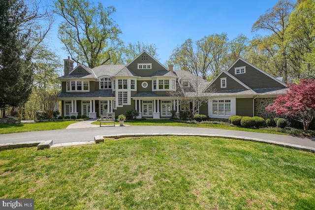 view of front of home with french doors, a chimney, and a front lawn