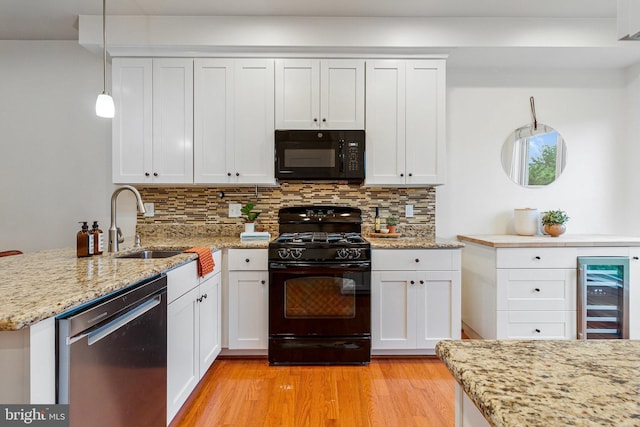 kitchen with black appliances, a sink, beverage cooler, a peninsula, and backsplash