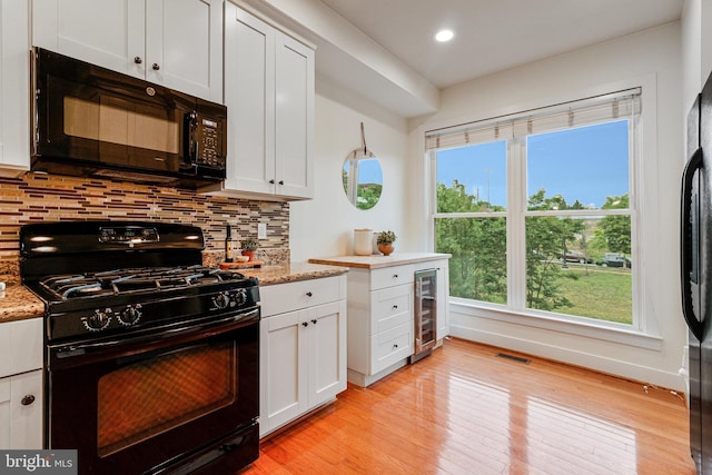 kitchen with black appliances, wine cooler, decorative backsplash, light wood-type flooring, and recessed lighting