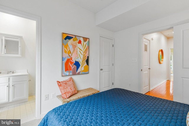 bedroom featuring a sink, baseboards, and light wood-type flooring