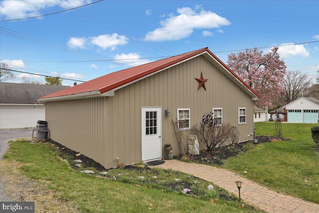 exterior space with a yard, metal roof, and an outbuilding