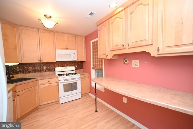 kitchen with light brown cabinets, white appliances, backsplash, visible vents, and a sink