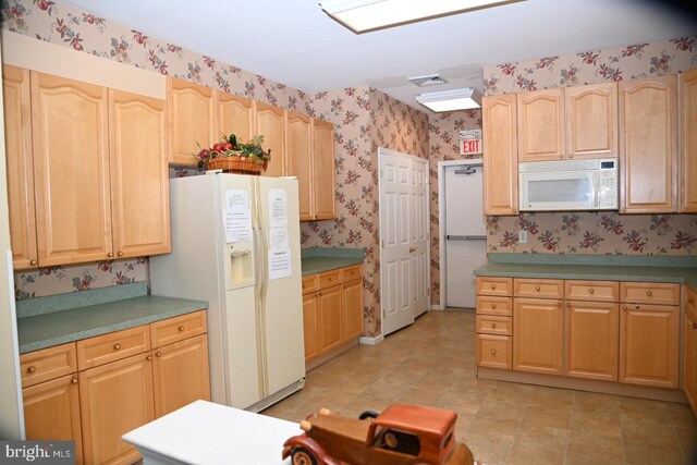 kitchen with visible vents, wallpapered walls, white appliances, and light brown cabinetry