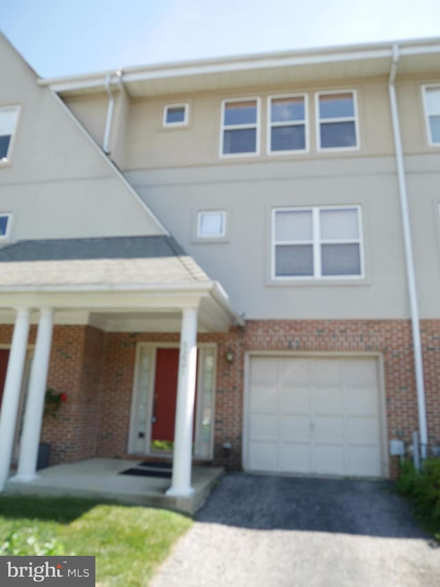 view of front of home featuring stucco siding, driveway, and brick siding