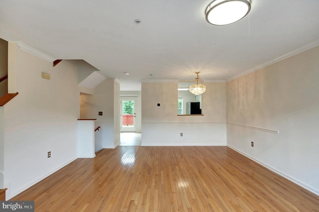 unfurnished living room with light wood finished floors, a chandelier, baseboards, and ornamental molding
