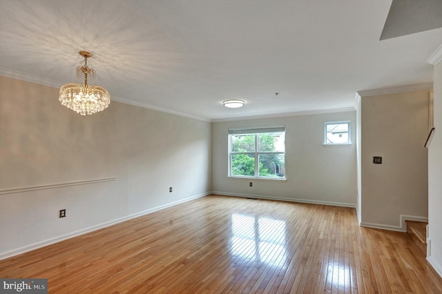 unfurnished room with ornamental molding, a notable chandelier, light wood-style flooring, and baseboards