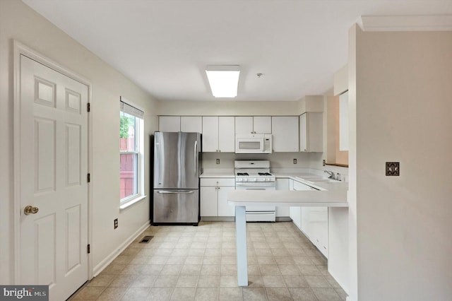 kitchen with a sink, visible vents, baseboards, white appliances, and light countertops
