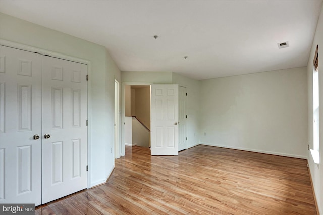 unfurnished bedroom featuring a closet, light wood-type flooring, and baseboards