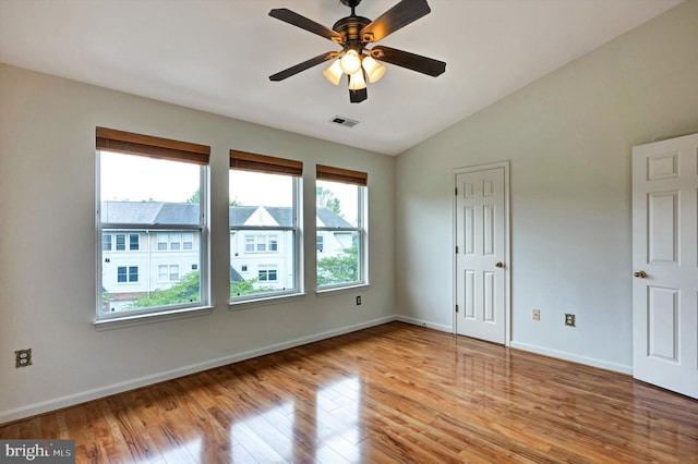 spare room with visible vents, vaulted ceiling, ceiling fan, baseboards, and light wood-style floors