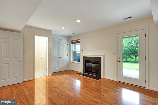 unfurnished living room featuring light wood finished floors, visible vents, a fireplace with flush hearth, and recessed lighting