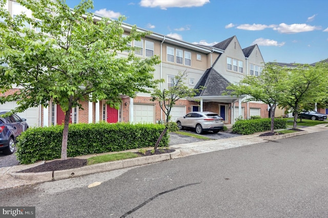 townhome / multi-family property featuring brick siding, stucco siding, and aphalt driveway