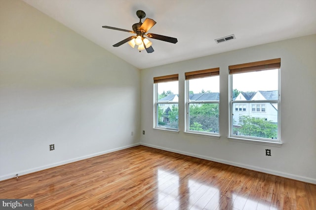 empty room with lofted ceiling, a ceiling fan, baseboards, visible vents, and light wood-type flooring