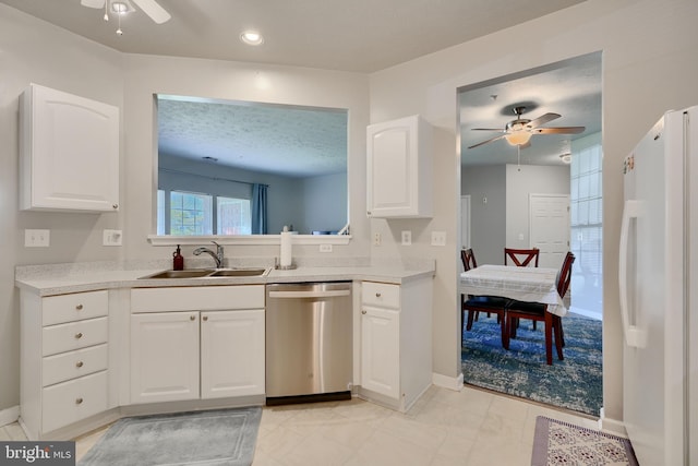 kitchen with ceiling fan, a sink, light countertops, freestanding refrigerator, and stainless steel dishwasher