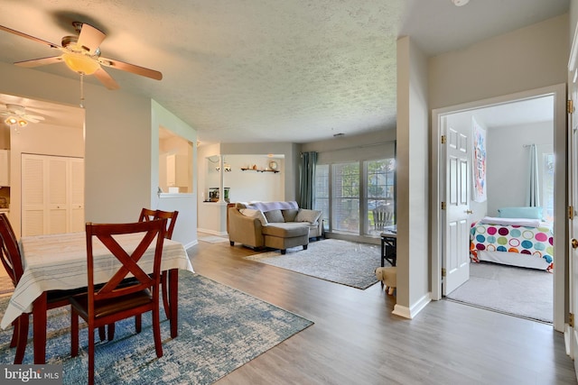 dining area with a ceiling fan, baseboards, wood finished floors, and a textured ceiling
