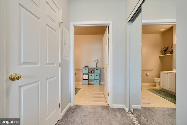 hall with light tile patterned floors, baseboards, and light carpet