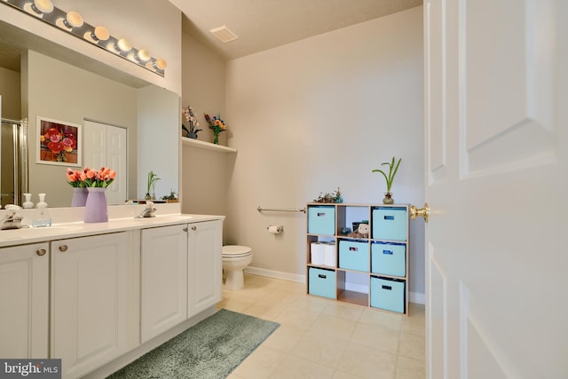 bathroom with a sink, tile patterned floors, toilet, and double vanity