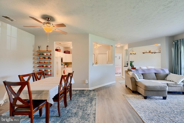dining space featuring visible vents, dark wood-style flooring, baseboards, a textured ceiling, and a ceiling fan
