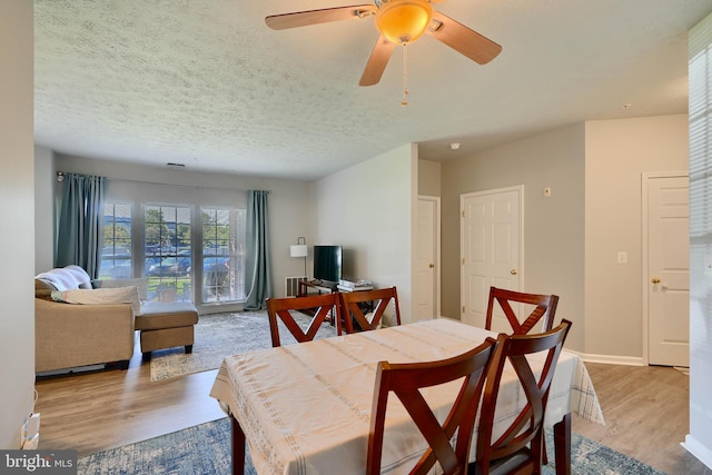 dining space with baseboards, a ceiling fan, a textured ceiling, and wood finished floors